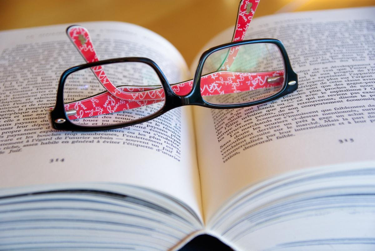 photo of reading glasses lying on top of book