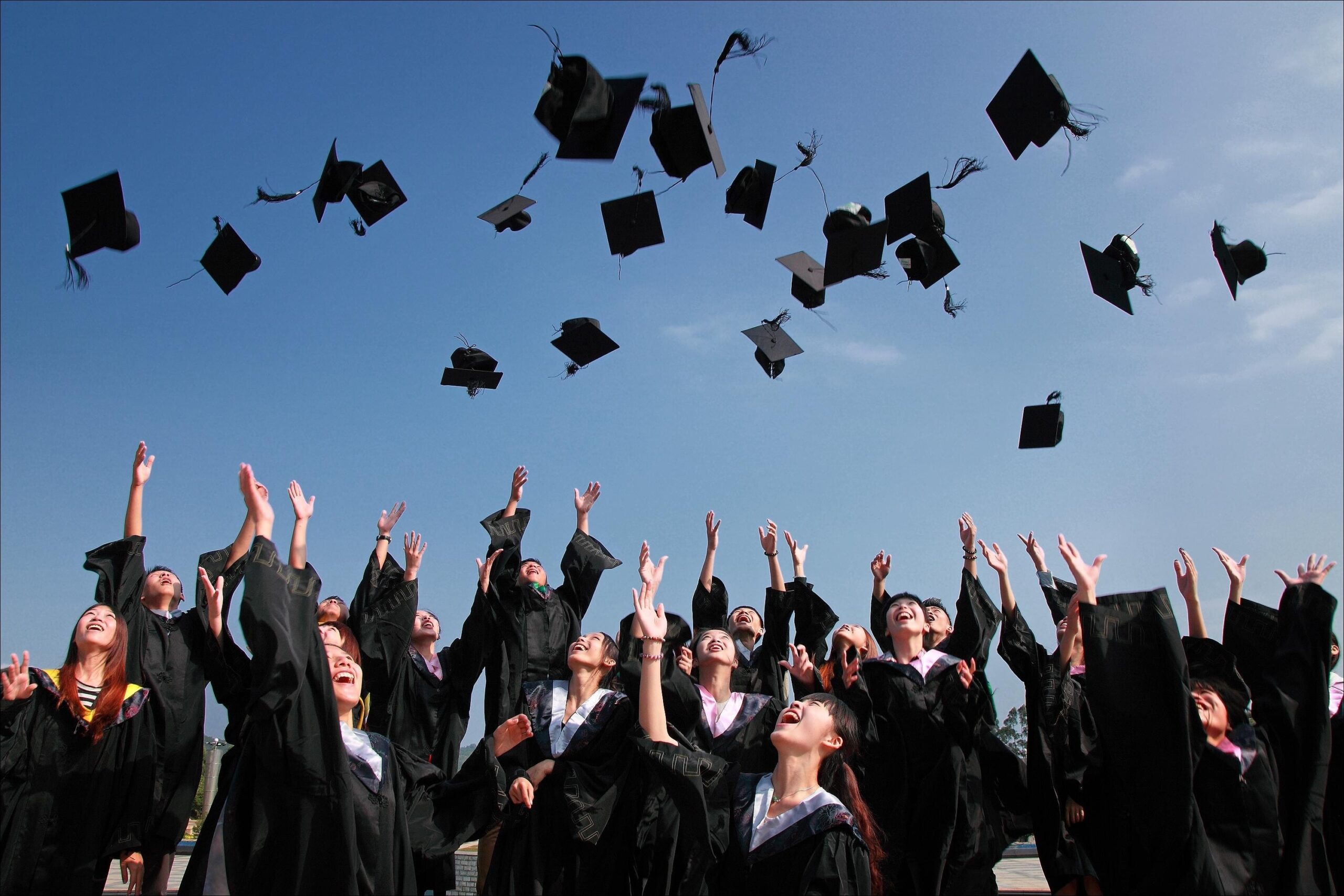 photo of graduates throwing caps into the air