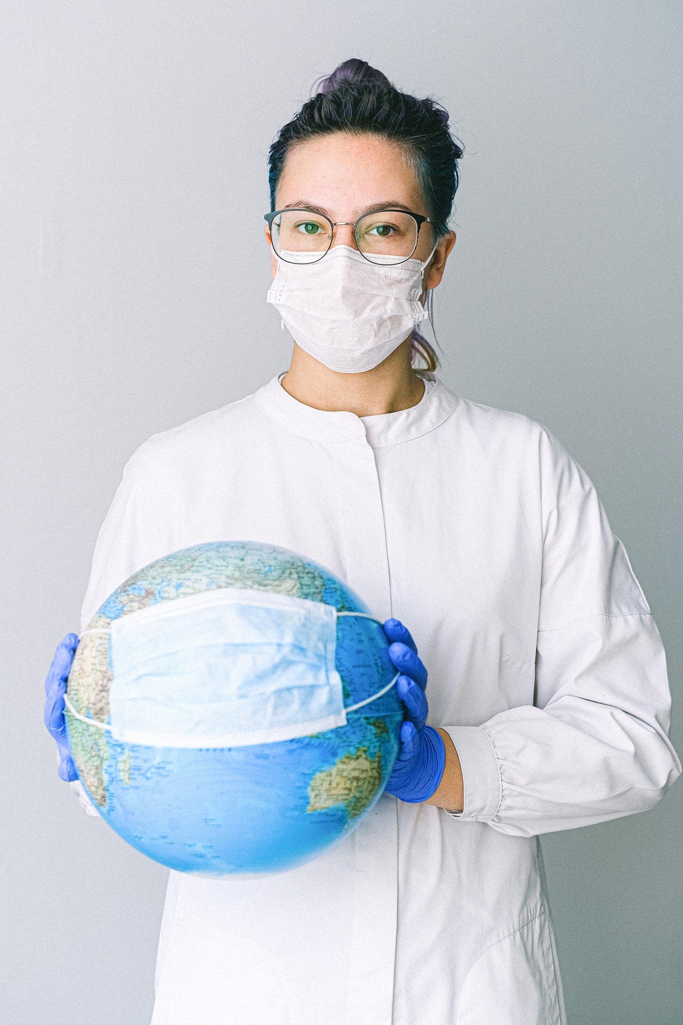 healthcare worker who is masked holding a globe with a mask on it